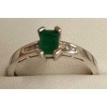 AN EMERALD RING WITH DIAMOND SHOULDERS SET IN 18ct WHITE GOLD