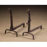 A Pair of Wrought Iron Fire Dogs with loop-ended ratcheted stems and adjustable spit hooks with