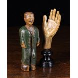 A Naively Carved Wooden Figure of a man wearing a green painted suit and black clogs,