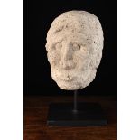 A Romanesque Carved Stone Head 24 cm high (9½") mounted on a display stand 40 cm overall (15¾").