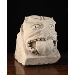 A Medieval Stone Corbel carved with a Grotesque sticking out it's tongue, 20 cm high, 15 cm wide,