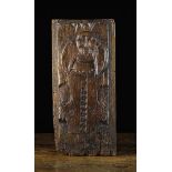 A 16th Century Oak Panel naively carved with a bold headed cherub on a piece of scrolled parchment,