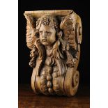 A Large 17th Century Flemish Oak Corbel carved in relief with a winged cherub's head above fruiting
