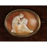 A Victorian Carved Shell Cameo Brooch finely carved with a classical female figure sat with amphora.