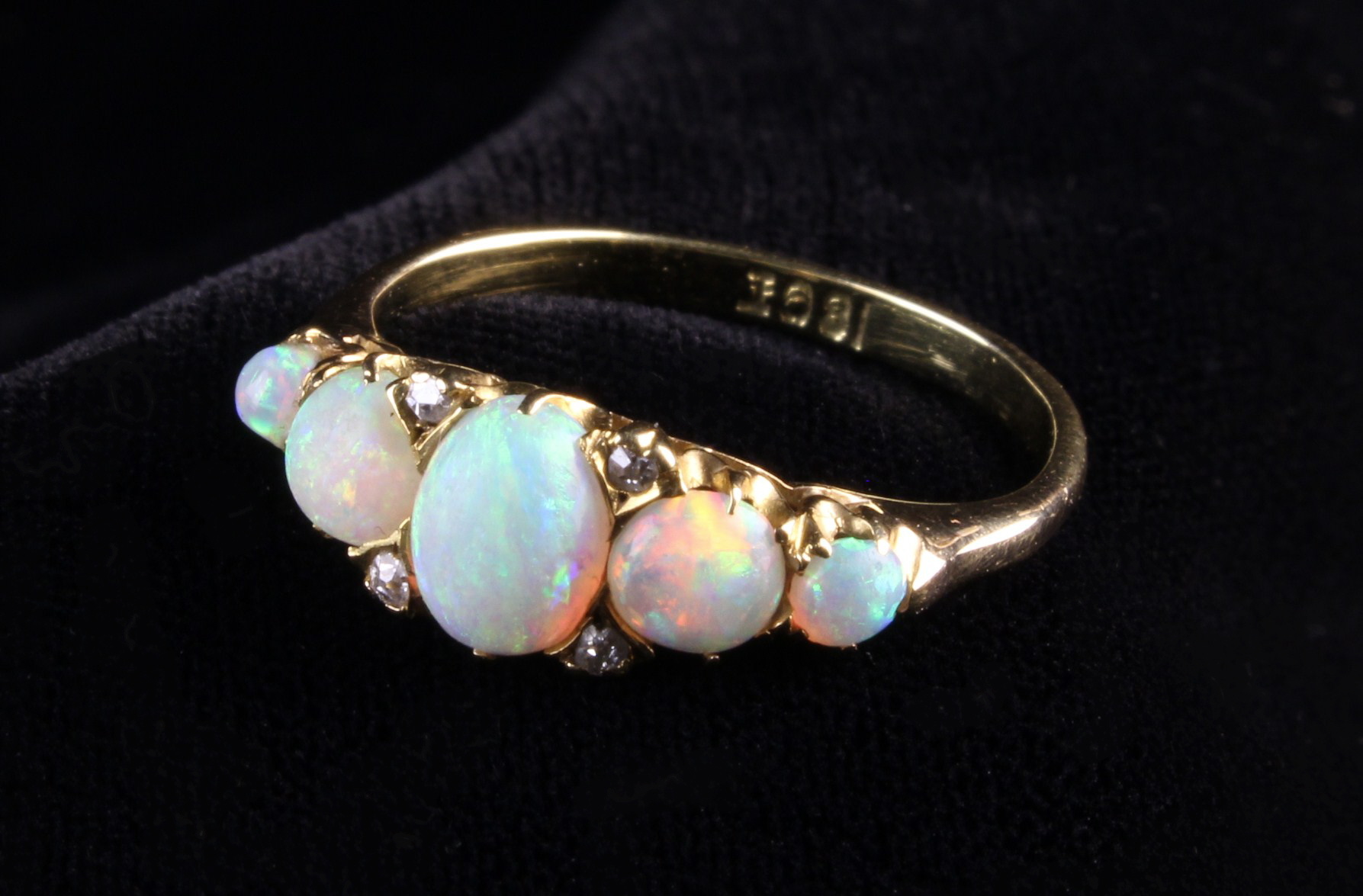 A Lady's 18 Carat Yellow Gold Ring set with five opals and four small diamonds flanking the central