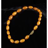 An Amber Bead Necklace composed of a string of graduated ovoid amber beads divided by small amber