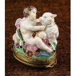 A Delightful 19th Century Porcelain Patchbox modelled as Cupid with his bow and arrows sat upon a