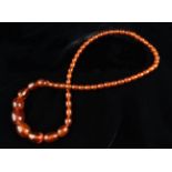 A String Necklace of Cherry Amber Beads of graduated ovoid form, 28" (71 cm) in length, approx 71g.