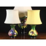 Three 20th Century Moorcroft Lamps: The largest of baluster form decorated with clematis on a dark