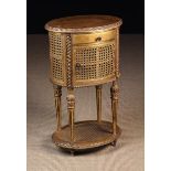 A Small Louis XVI Style Gilded Bedside Cabinet of oval form with caned sides and under-shelf.