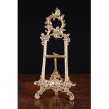 An Ornate Brass Table Easel cast with Rococo style ornamentation and supporting a painted
