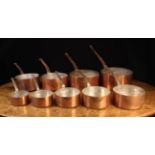 A Set of Nine Graduated Copper Culinary Pans with tinned interiors on iron loop ended handles,