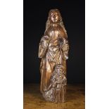 A 16th Century Dark patinated Wood Carving of a female figure depicted with long wavy hair wearing