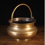 A 17th/Early 18th Century Bronze Cooking Pot with swing handle, on a raised foot,