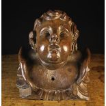 A Large Carved Oak Architectural Ceiling Boss in the form of a cherub's head with curly hair and