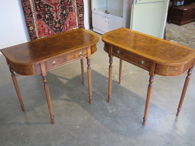 A pair of walnut D shaped side tables with a single drawer on turned reeded legs, made by a local