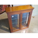 A mahogany two door show case with three glass shelves, 65.5cm x 23.5cm x 73.5cm