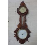 A late Victorian walnut barometer clock with thermometer, extensively carved with a nautical