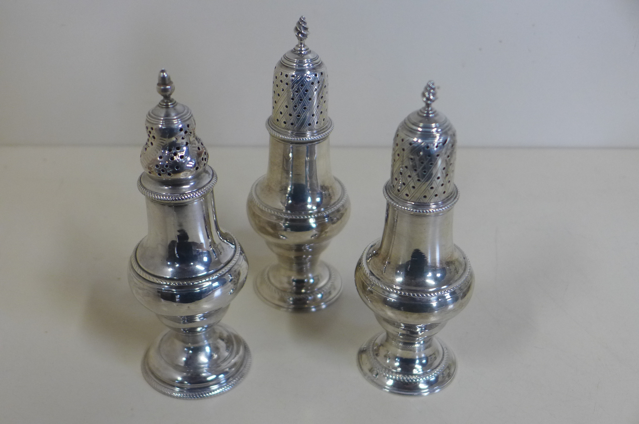 A pair of Georgian silver peppers, London 1816/17 - 15cm tall, maker TI, and a single pepper,