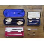 A pair of boxed silver fruit spoons, a boxed silver christening set, a boxed silver fork, a silver