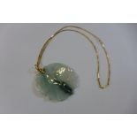 A carved jade pendant of two carp, 5cm wide, on a gold chain, 50cm long, tests to approx 22ct,