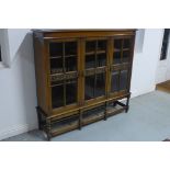 An oak three door glazed bookcase on barley twist supports, 140cm H x 150cm W x 38cm D