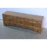 A carved elm Chinese cabinet with five small drawers above six cupboard doors and two hidden