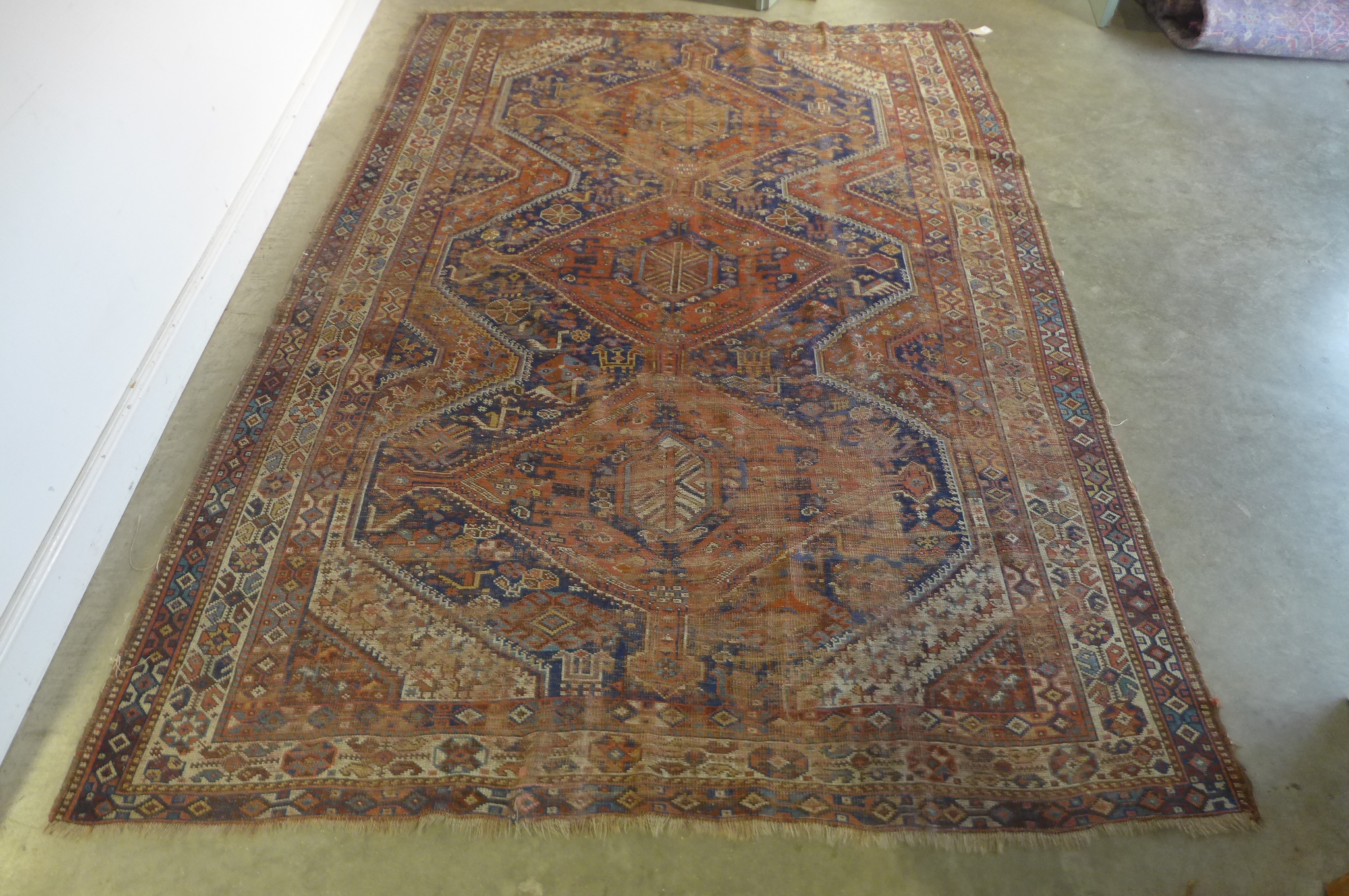 A vintage hand knotted Eastern woollen rug, 302cm x 206cm, in worn condition and some fading