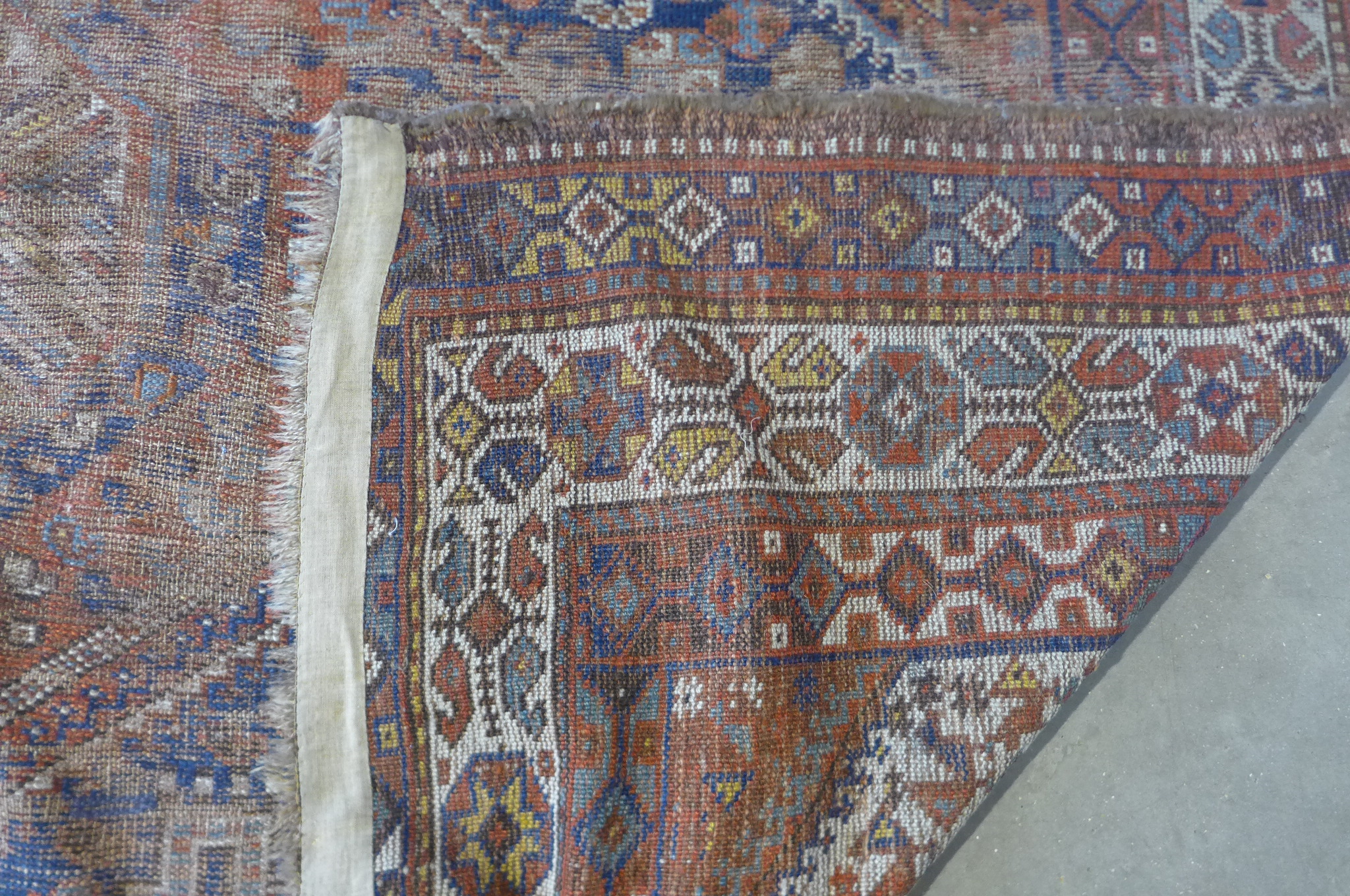 A vintage hand knotted Eastern woollen rug, 302cm x 206cm, in worn condition and some fading - Image 8 of 8