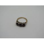 An 18ct gold garnet three stone ring, size J 1/2 - weight approx 4.3 grams, some rubbing to stones