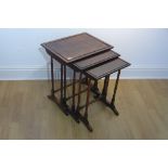 A nest of three rosewood side tables on turned supports, 58cm tall x 50cm x 38cm