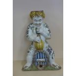 A large Majolica wine cistern in the form of a Putti sitting on a barrel holding a cup and flagon,