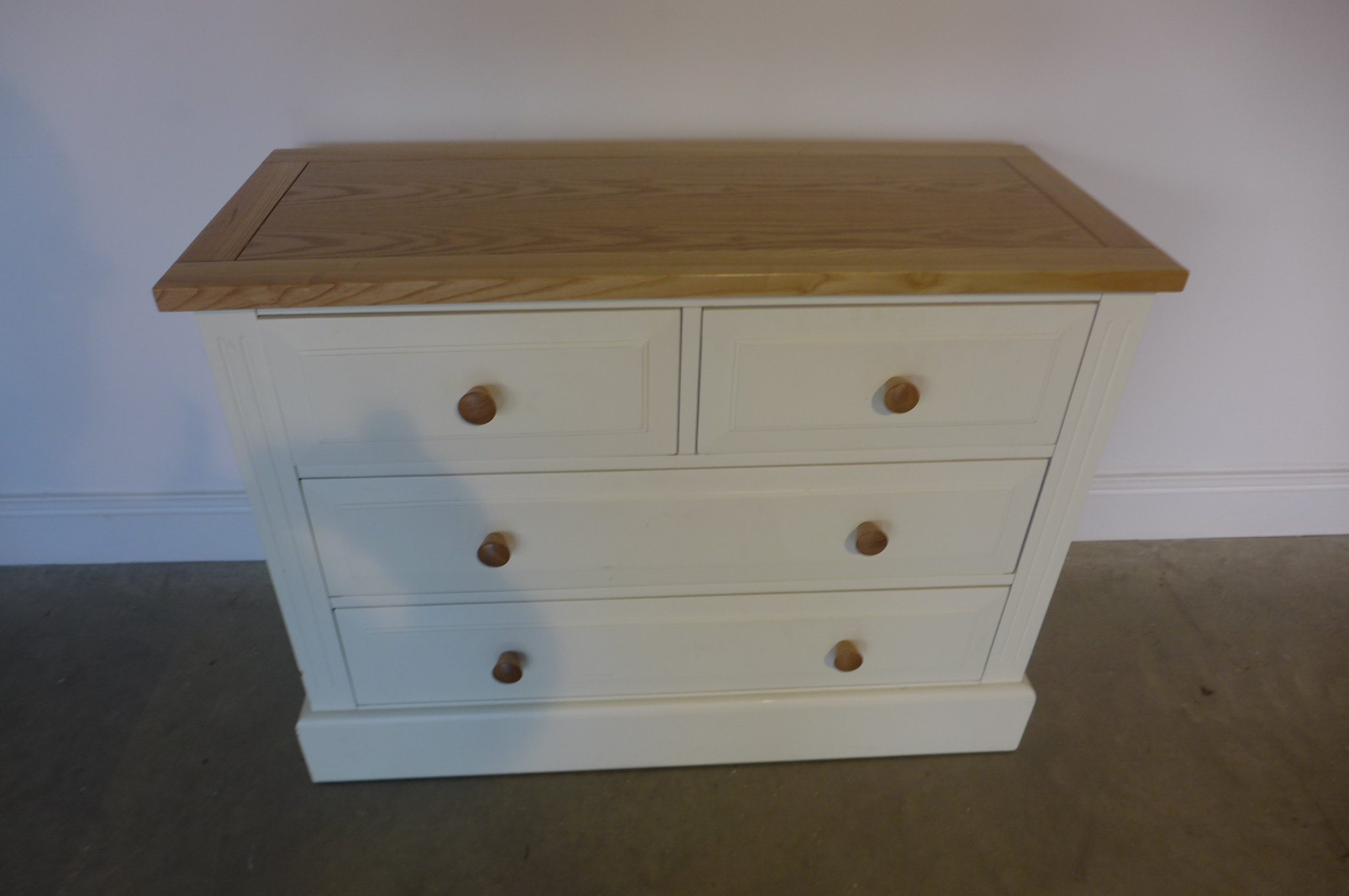 A painted white chest with four drawers, 102cm wide, 76cm high