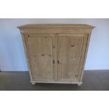 A stripped pine Victorian two door cupboard with a shelved interior, 118cm tall x 110cm x 45cm -