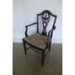 An Edwardian mahogany elbow chair with a carved Shereton style splat