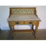 A Victorian pine two drawer marble top wash stand with a tiled back - 97cm tall x 92cm x 49cm