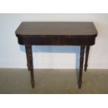 A 19th century rosewood fold over card table on turned supports, 74cm tall x 92cm