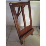 An early 1900s folding mahogany artist easel by Roberson and Co, with ratchet mechanism, and a brush