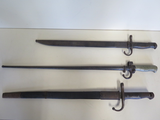 A spike bayonet with scabbard, total length 65cm, and two other bayonets