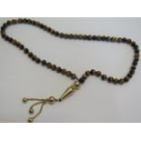 A bracelet of cats eye worry beads with gilt metal end