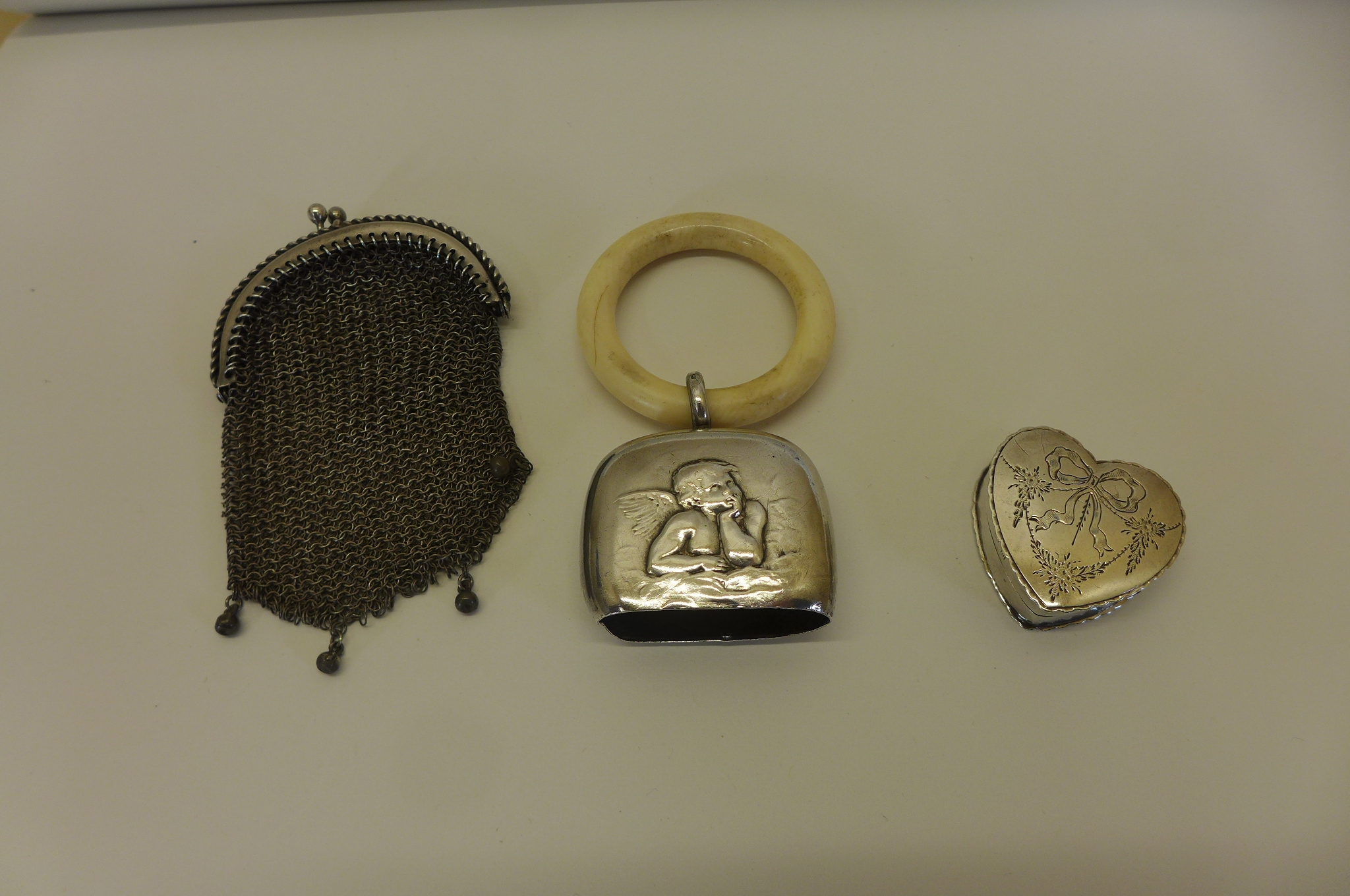 A silver heart shaped pill box with engraved ribbon and floral decoration, a silver coin purse,