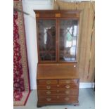 An Edwardian bureau bookcase with a two door glazed top over a fitted interior above five oak