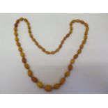 A good string of deep honey colour amber oval shaped beads in knotted string, string length 68cm,