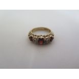 A hallmarked 9ct gold ring set with three large garnet colour stones ad four white stones, ring size