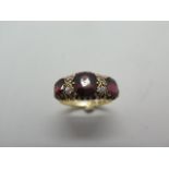 An 18ct gold diamond and garnet ring, set with three oval garnets each divided by the two