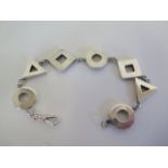 An abstract silver bracelet made up of alternate triangular and circular links with pierced