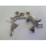 A silver charm bracelet with various silver and white metal charms, including Big Ben, Brighton