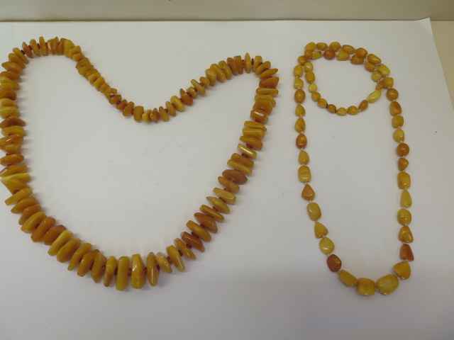 Two strings of natural polished amber beads, deep honey and egg yolk colours, larger string 74cm