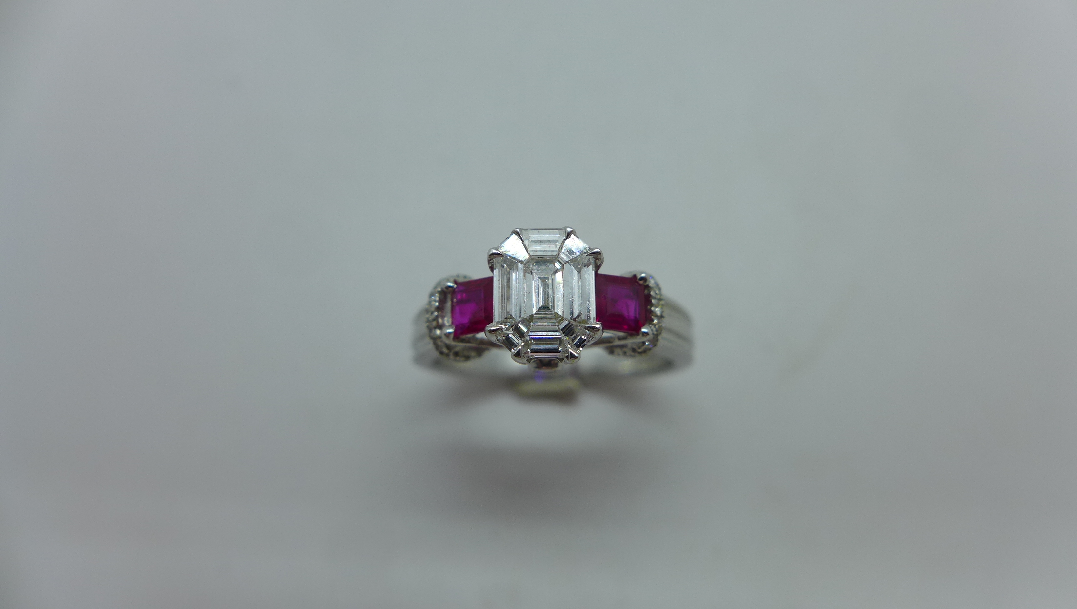 An 18ct white gold diamond and ruby ring with a centre 9 piece diamond, emerald cut measuring 7mm