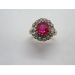 An 18ct synthetic ruby and diamond cluster ring, the central stone (Red synthetic corundum )having a